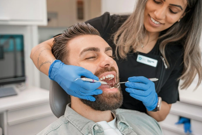 Dentista con guantes azules revisando a un paciente